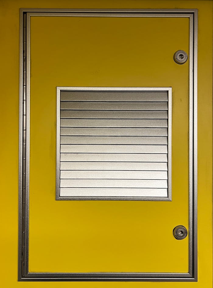 Bright yellow metal door featuring a silver ventilation panel in a minimalist design.