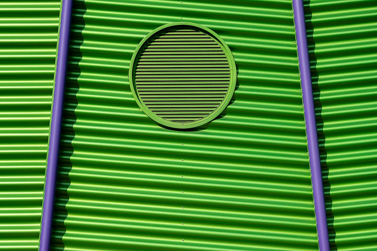 Vivid green corrugated metal wall featuring a circular vent and purple accents, creating a striking visual contrast.